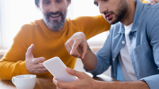 Equity to access in college planning information: teenage son looking at phone with his father