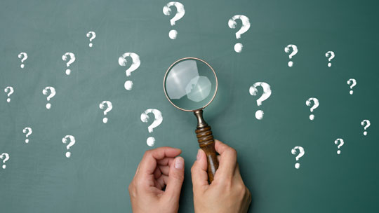 Blog on 2023 Graduate and Online Research: Magnifying glass hovering over question marks. 