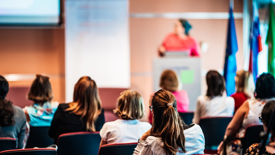 Blog on Fundraising Conferences: Image of audience listing to a presenter at a conference
