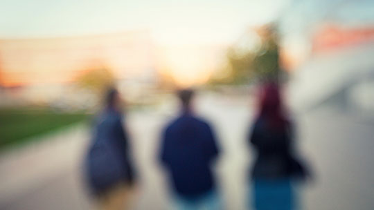 Blog on campus safety: Blurred image of three people walking across a campus.