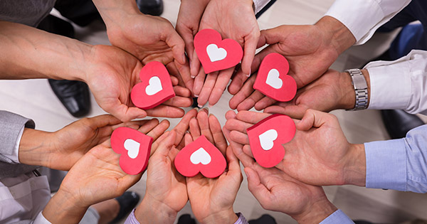 Stewardship with heart: hands holding little paper hearts