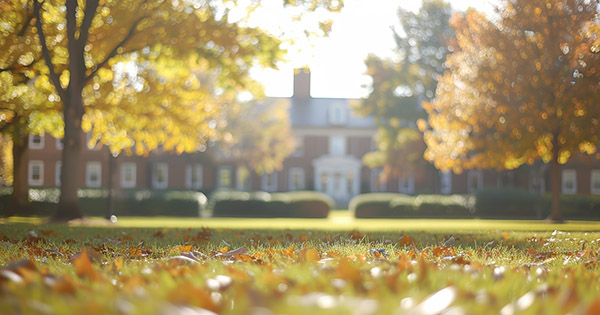 Blog on college closings: Blurred image of a campus building surround by trees.