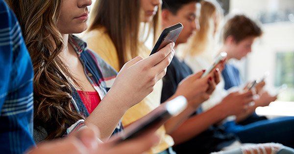 Image of high school students looking at the cell phones