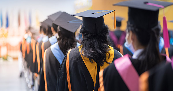 Blog on student satisfaction and alumni connection: image of a line of graduates in cap and gown.