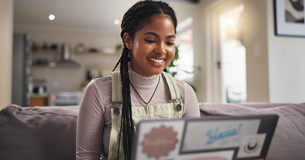 Blog on why students reach out to colleges: Image of a female high school student on her laptop in her living room