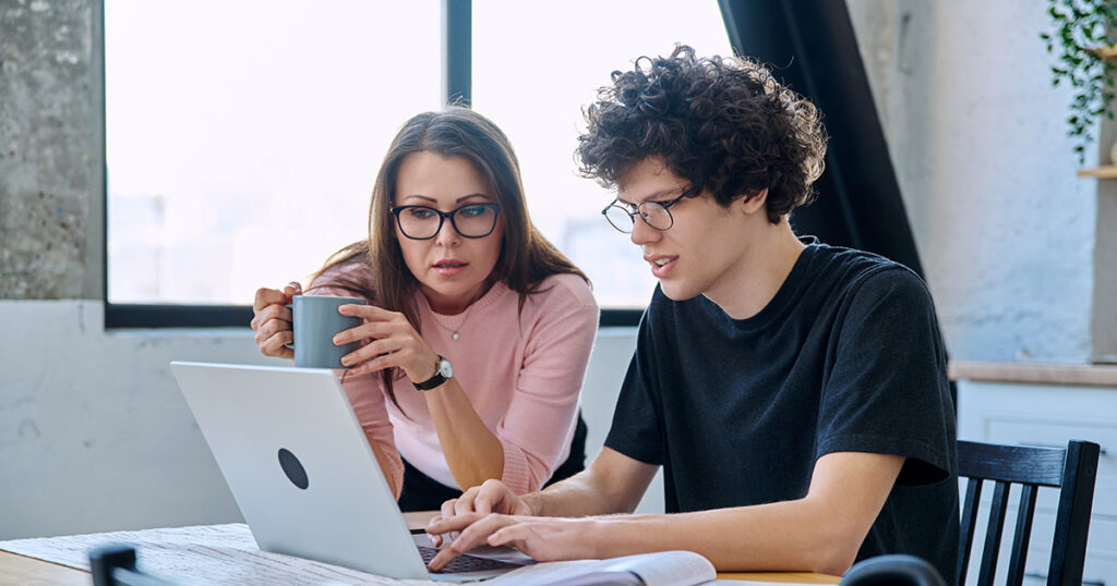 Mother looking at a computer screen with her teenage son