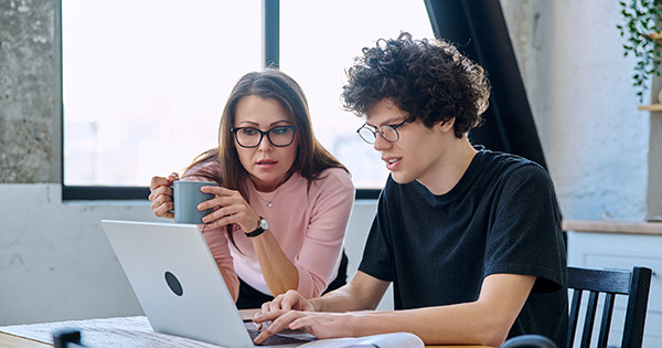 Mother looking at a computer screen with her teenage son