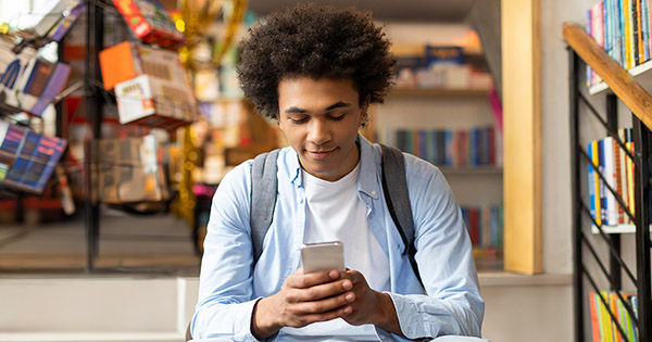 Blog on college digital advertising: Male student sitting on steps looking at his phone