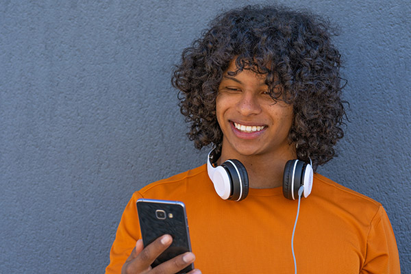 Blog on Stealth to Seen: Image of male student with headphones looking at his phone